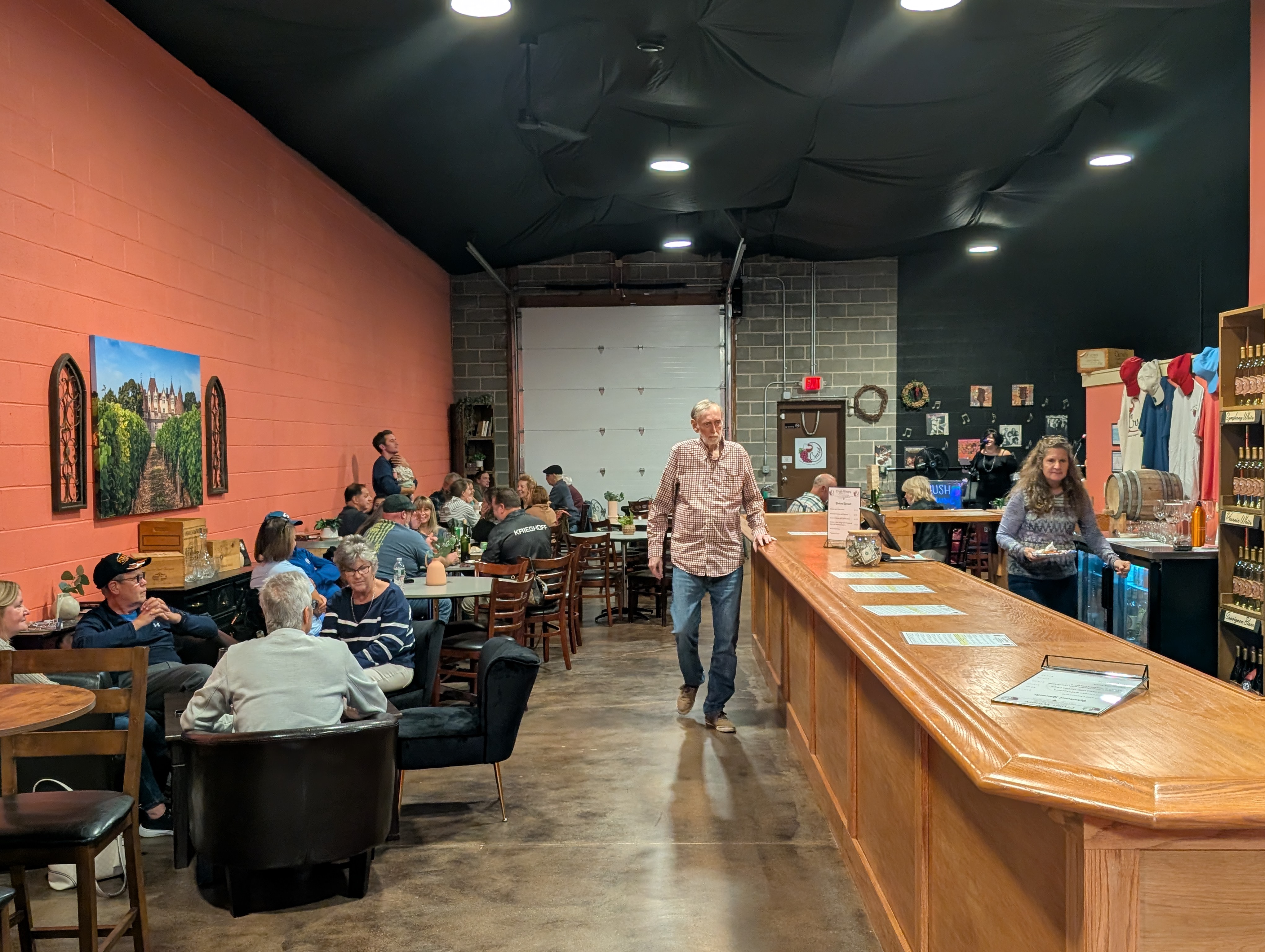 A lively afternoon at Crush Winery with guests gathered beside the long wood bar and wine cabinet
